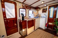 Interior of a 2016 custom trawler with wooden cabinetry and compact kitchen area.