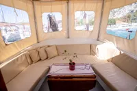 Cozy seating area on a 2016 custom trawler with beige cushions and a small table.