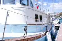 Custom 2016 trawler docked at marina, featuring blue and white hull with wooden accents.