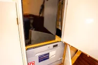 Compact refrigerator in 2016 Custom Trawler interior, wooden cabinetry, open doors.