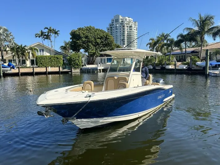 T/t Living With E's Yacht Photos Pics 2018 Scout 255LXF boat on a sunny waterfront with palm trees and buildings.