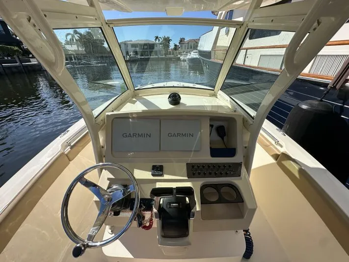 T/t Living With E's Yacht Photos Pics 2018 Scout 255LXF boat cockpit with Garmin navigation system, steering wheel, and waterfront view.