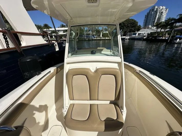 T/t Living With E's Yacht Photos Pics 2018 Scout 255LXF boat interior with tan seating, docked by waterfront buildings.