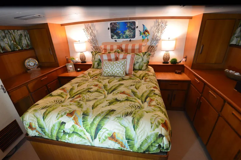  Yacht Photos Pics Luxurious 1990 Jefferson 52 Marquessa ED yacht bedroom with tropical decor and wooden cabinetry.