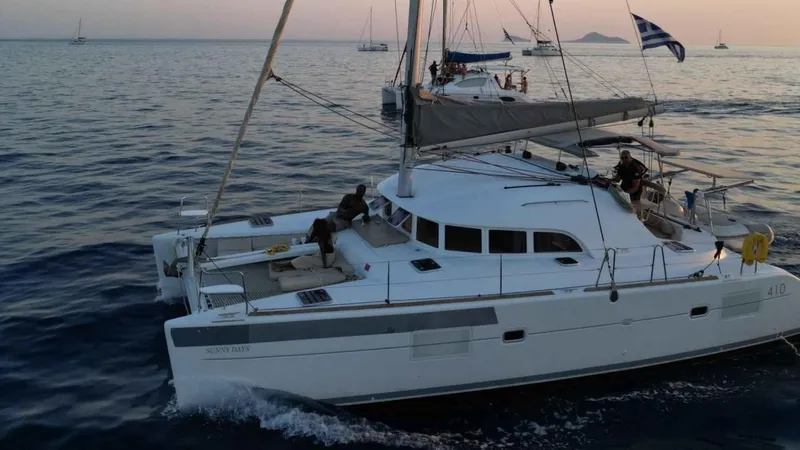 Sunny Days Yacht Photos Pics 2013 Lagoon 380 S2 catamaran sailing at sunset with people on deck.