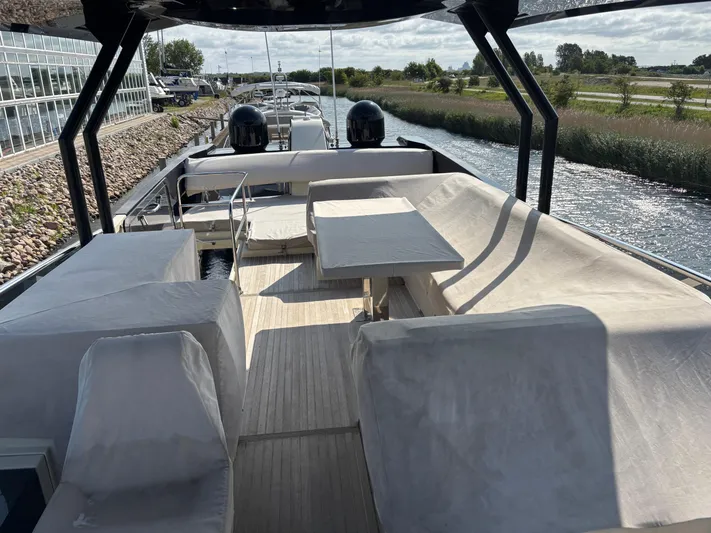  Yacht Photos Pics 2015 Beneteau Monte Carlo 6 yacht deck with seating and table, docked by a canal.