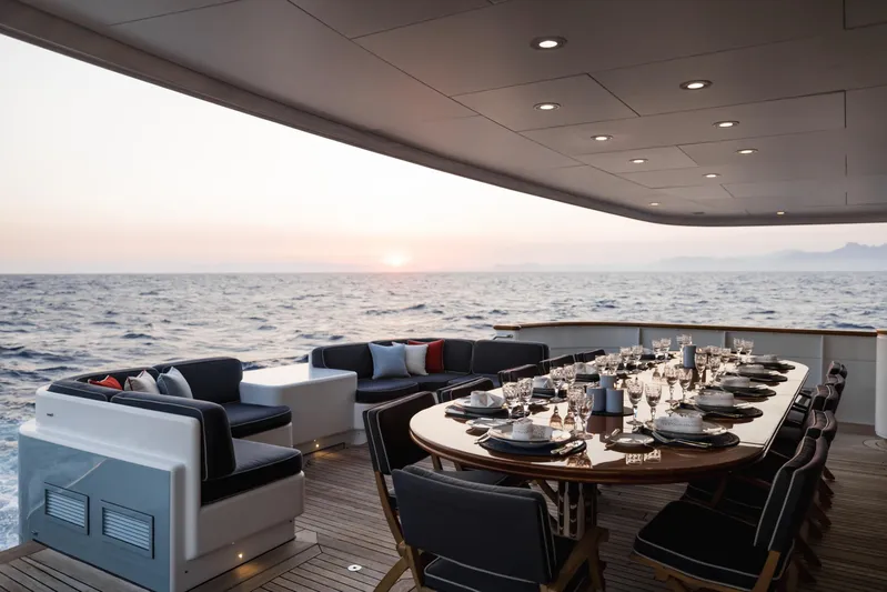 Olympus Yacht Photos Pics Luxurious dining setup on 1996 Feadship motor yacht with ocean view at sunset.