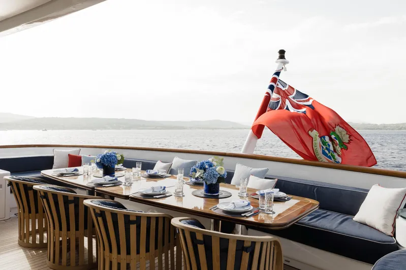 Olympus Yacht Photos Pics Luxurious dining area on 1996 Feadship motor yacht with elegant table setting and flag.
