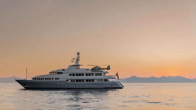 Olympus Yacht Photos Pics Luxurious 1996 Feadship motor yacht at sunset, featuring a helicopter on deck.