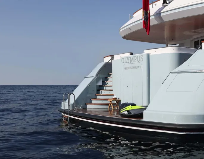 Olympus Yacht Photos Pics Alt text: "1996 Feadship motor yacht with steps leading to the ocean, featuring a red flag."