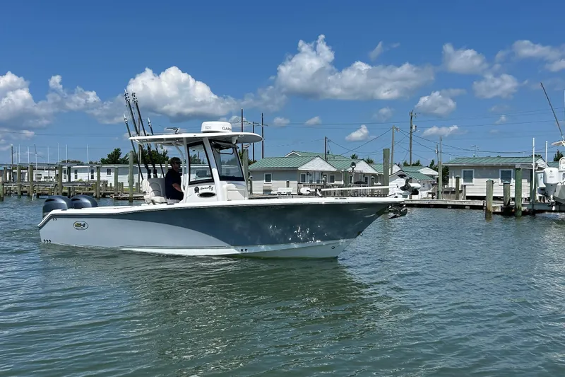  Yacht Photos Pics 2021 Sea Hunt Gamefish 25 boat on water near docks under blue sky.