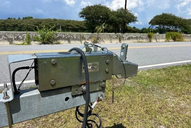  Yacht Photos Pics Trailer hitch mechanism for 2021 Sea Hunt Gamefish 25 on roadside, with trees and sky background.