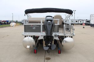 2025 Sun Tracker Party Barge 18 DLX pontoon boat, rear view with motor, parked outdoors.