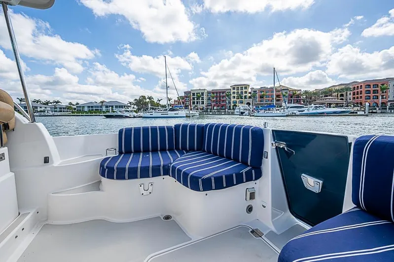 Phoebe Mcbean Yacht Photos Pics 2011 Back Cove 30 boat with striped seating, marina view, colorful buildings in background.