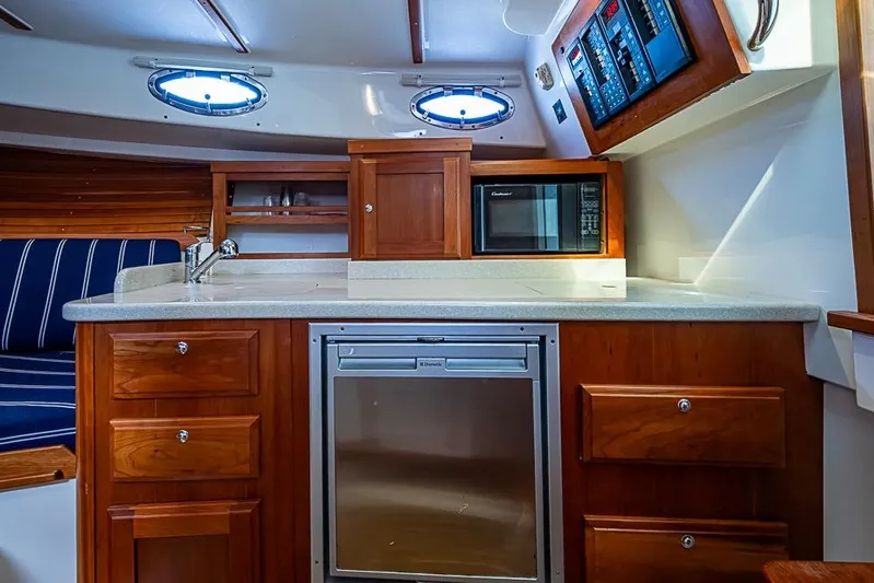 Phoebe Mcbean Yacht Photos Pics 2011 Back Cove 30 yacht interior with kitchenette, featuring wood cabinetry and modern appliances.