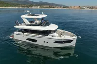 Luxury 2021 Absolute 52 Navetta yacht cruising on calm waters near scenic coastline.