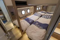 Luxurious cabin interior of 2021 Absolute 52 Navetta yacht with twin beds and porthole windows.