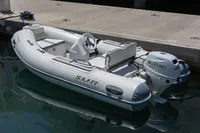 Inflatable boat with Suzuki outboard motor docked at marina.