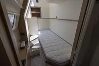 Cozy cabin interior of 2021 Absolute 52 Navetta yacht with single bed and storage shelves.