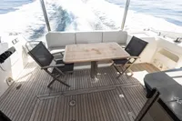 Outdoor seating area on 2021 Absolute 52 Navetta yacht with wooden deck and table.
