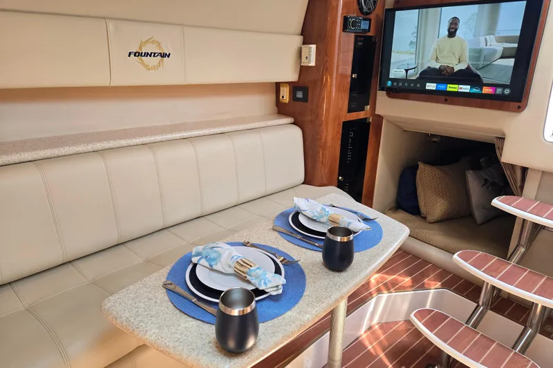 Let's Go! Yacht Photos Pics Luxurious interior of 2007 Fountain 38 Express Cruiser with elegant dining setup and entertainment system.
