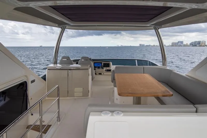  Yacht Photos Pics Luxurious 2023 Absolute 62 Fly yacht interior with ocean view, featuring seating and table.