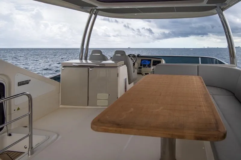  Yacht Photos Pics Luxurious 2023 Absolute 62 Fly yacht interior with ocean view, featuring a wooden table and seating.