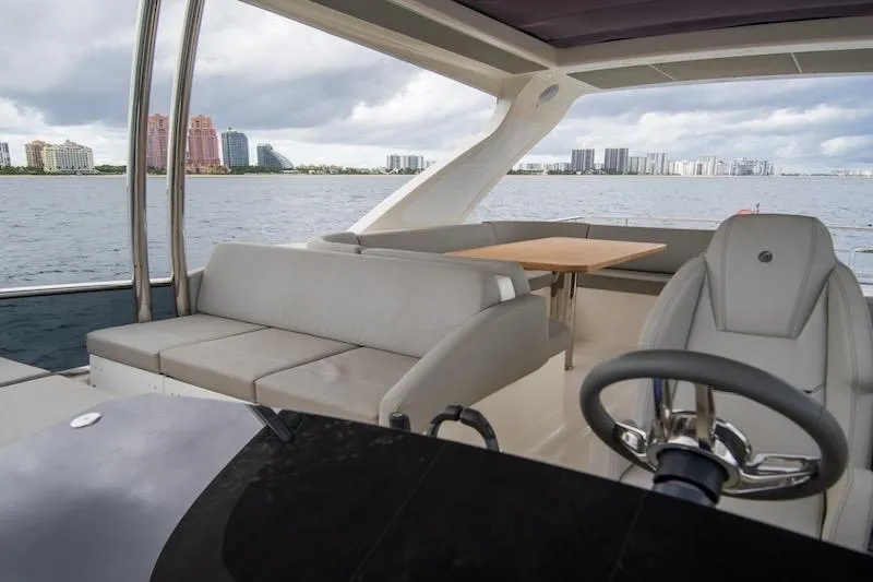  Yacht Photos Pics 2023 Absolute 62 Fly yacht interior with seating, table, and steering wheel, overlooking waterfront skyline.