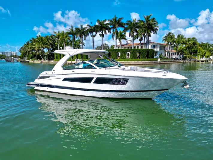  Yacht Photos Pics 2017 Four Winns H350 boat cruising on a sunny day near luxury waterfront homes.