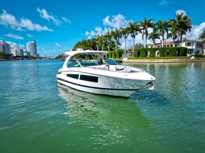  Yacht Photos Pics 2017 Four Winns H350 boat cruising on a sunny day with palm trees and cityscape.