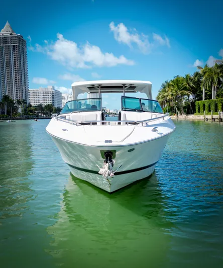  Yacht Photos Pics 2017 Four Winns H350 boat on calm water with cityscape and palm trees.