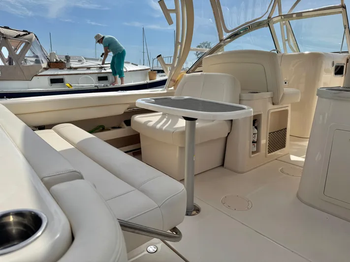 Bay Tripper Yacht Photos Pics 2019 Grady-White Freedom 307 boat interior with seating and table, docked near another vessel.