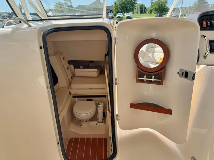Bay Tripper Yacht Photos Pics 2019 Grady-White Freedom 307 boat interior with compact bathroom and wooden accents.
