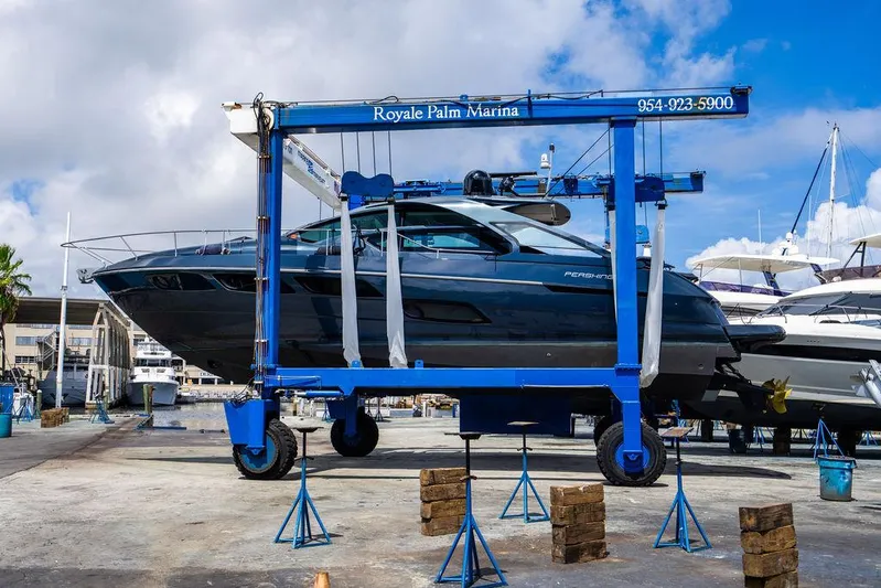 Two Bite Yacht Photos Pics 2018 Pershing 5x yacht at Royale Palm Marina, lifted by a blue boat hoist.