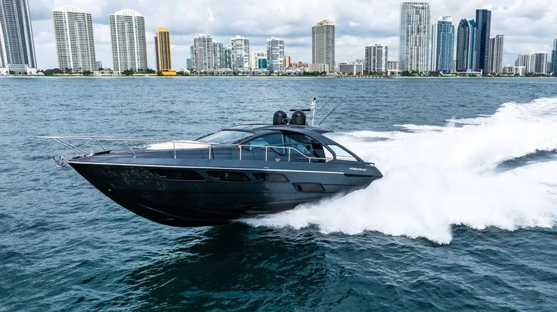 Two Bite Yacht Photos Pics 2018 Pershing 5x yacht cruising fast on water with city skyline in background.