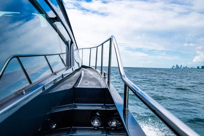 Two Bite Yacht Photos Pics 2018 Pershing 5x yacht cruising on open sea with city skyline in background.