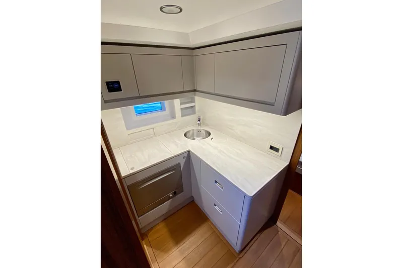  Yacht Photos Pics Compact modern yacht kitchen with sleek cabinetry, small sink, and window. Glacier 48, 2026 model.