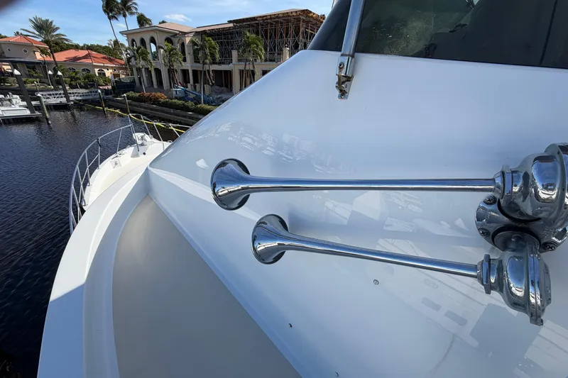  Yacht Photos Pics 1991 Hatteras 70 Motor Yacht with chrome horns, docked near luxury waterfront homes.