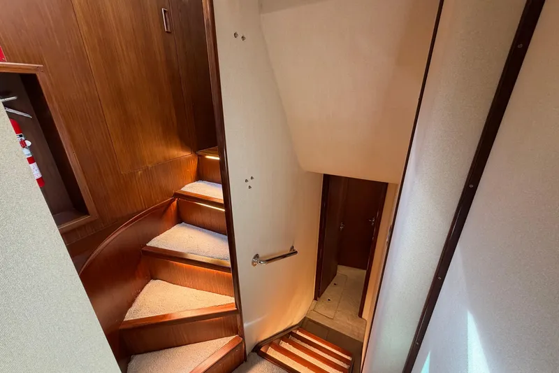  Yacht Photos Pics Staircase inside 1991 Hatteras 70 Motor Yacht with wooden paneling and carpeted steps.