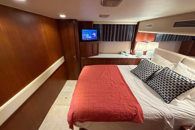  Yacht Photos Pics Luxurious bedroom interior of 1991 Hatteras 70 Motor Yacht with cozy bedding and TV.