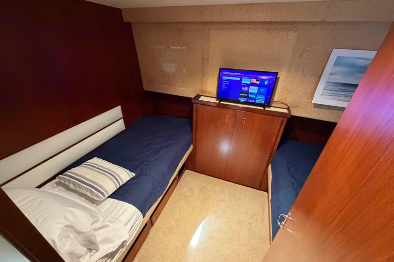  Yacht Photos Pics Twin bed cabin in 1991 Hatteras 70 Motor Yacht with TV and ocean artwork.