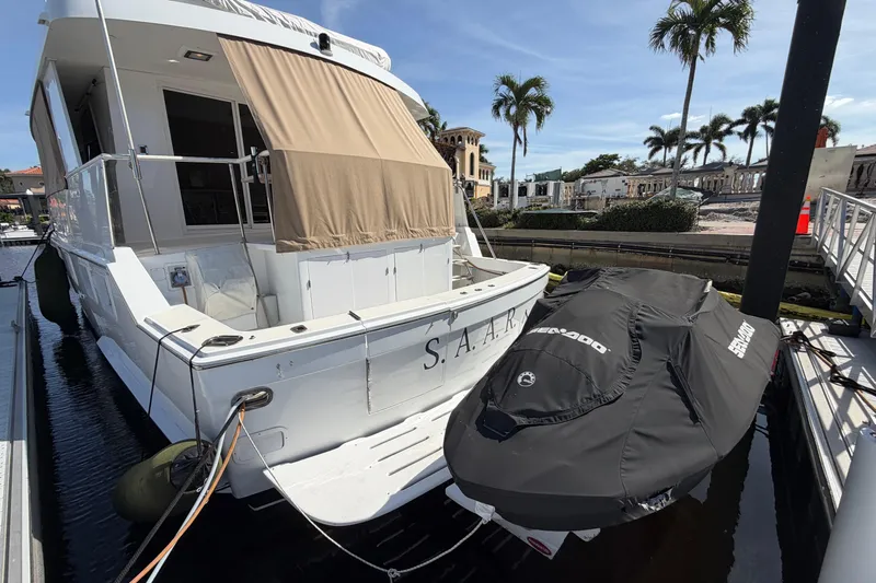  Yacht Photos Pics 1991 Hatteras 70 Motor Yacht docked with covered jet ski, palm trees in background.