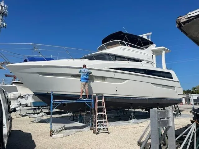  Yacht Photos Pics 2006 Carver 43 Motor Yacht on stands, person working on hull, clear blue sky.