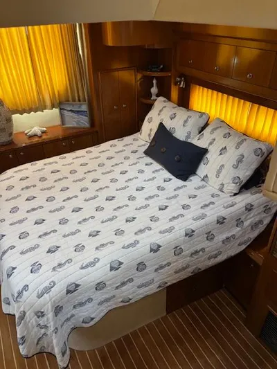  Yacht Photos Pics Cozy bedroom in 2006 Carver 43 Motor Yacht with nautical-themed bedding and warm lighting.