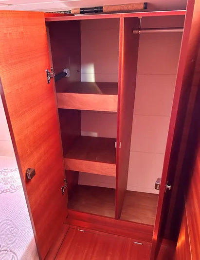 4770jg Yacht Photos Pics Wooden closet interior on 2015 Dufour 410 GL yacht, featuring shelves and hanging space.