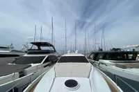 Luxury Pershing 70 yacht docked among other boats, 2015 model, under a cloudy sky.