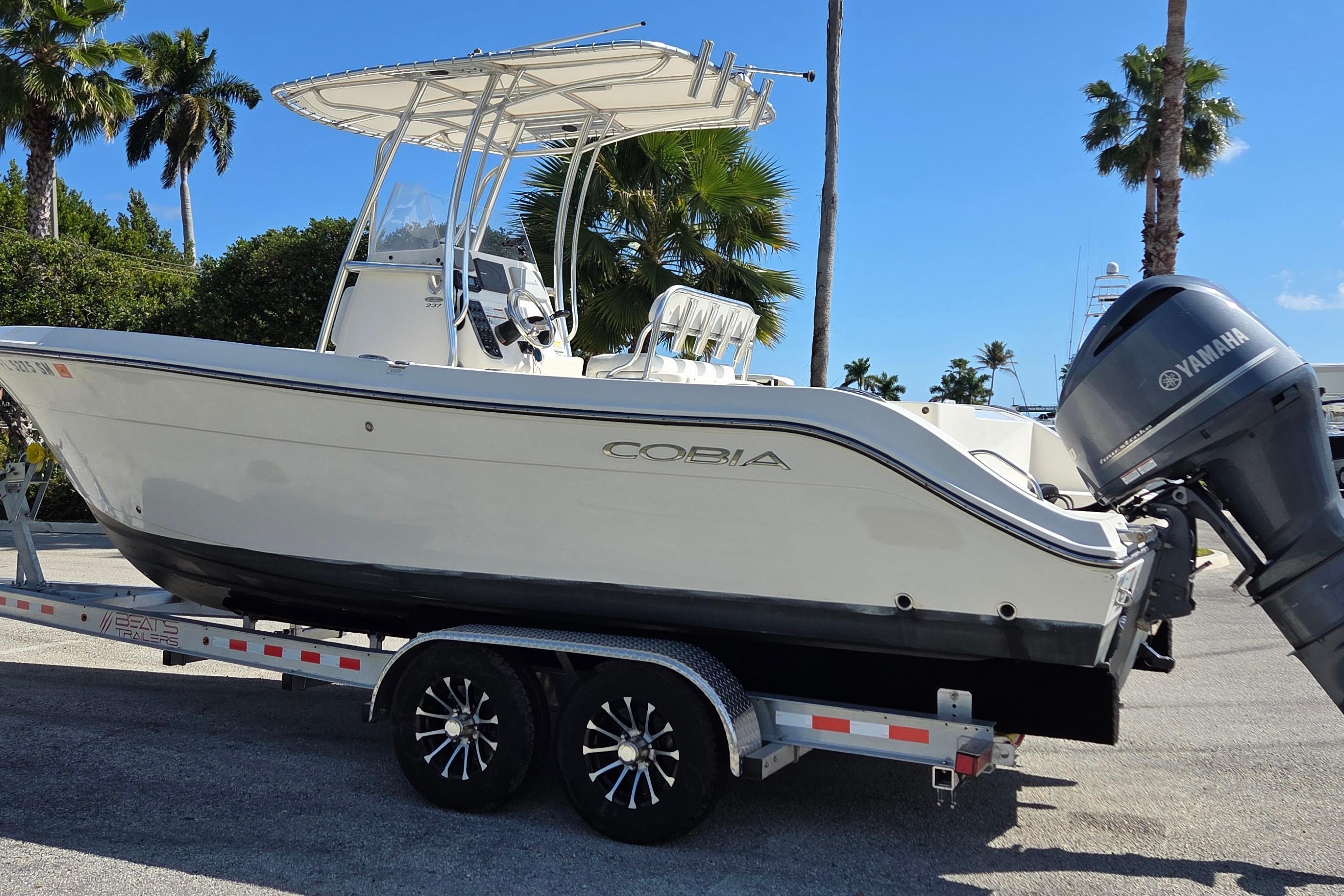 2020 Cobia 237 Center Console boat on trailer with Yamaha outboard, palm trees in background.