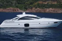 Luxury 2015 Pershing 70 yacht cruising on serene blue waters near a rocky coastline.