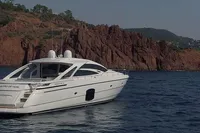 2015 Pershing 70 yacht cruising near rocky coastline.