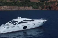 Luxury 2015 Pershing 70 yacht cruising in serene blue waters near rocky coastline.